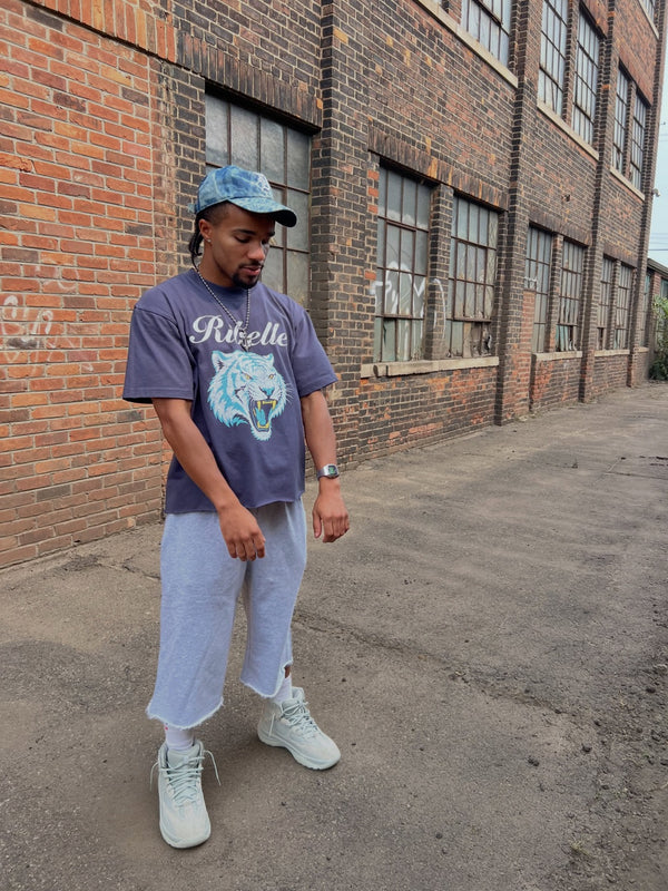 Customer in a washed purple Ribelle tiger-graphic tee on a warehouse street