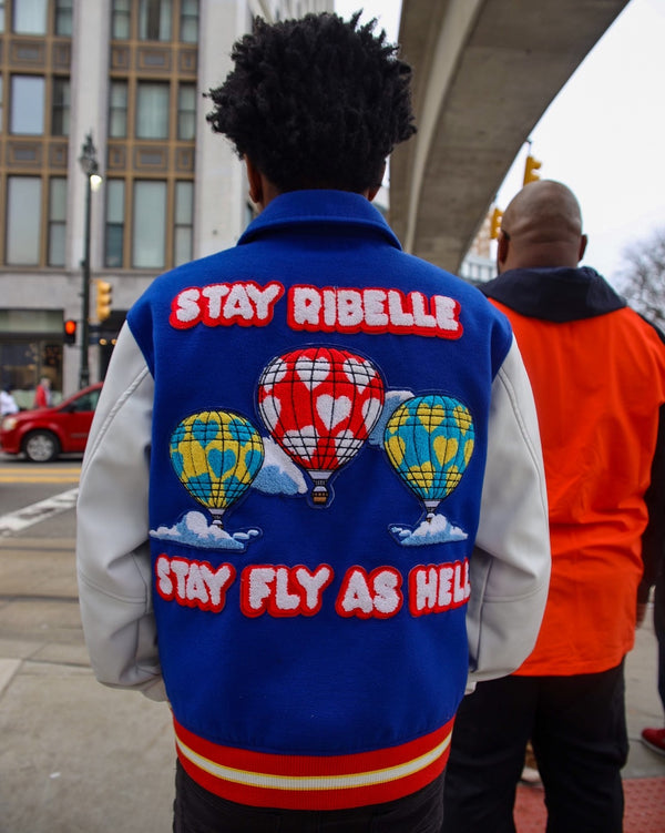 Back view of a Stay Ribelle varsity jacket with a Stay Fly As Hell hot-air-balloon print