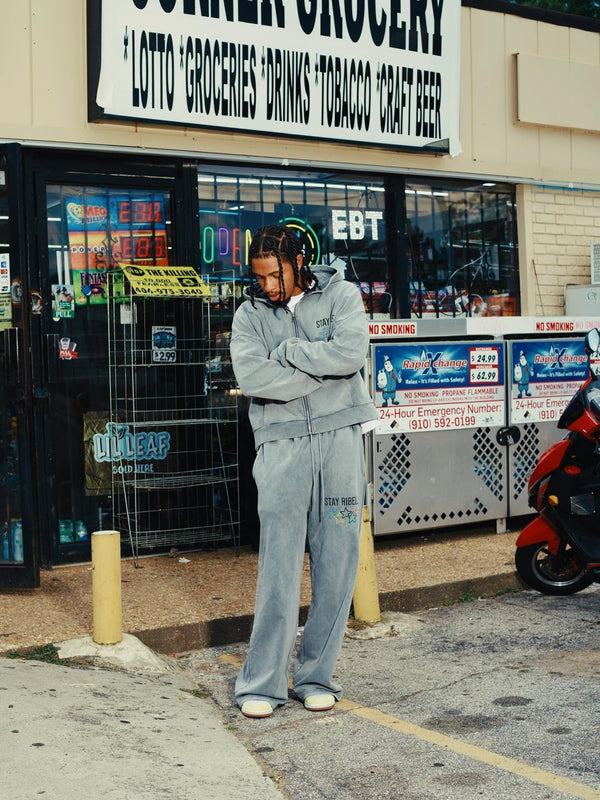 Customer in a washed light-blue Stay Ribelle sweatsuit outside a corner store