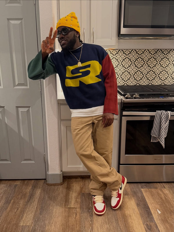 Customer in a navy Stay Ribelle logo sweater, tan pants and a yellow beanie